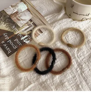 Set of five plush hair ties in earthy tones on a minimalist fabric background
