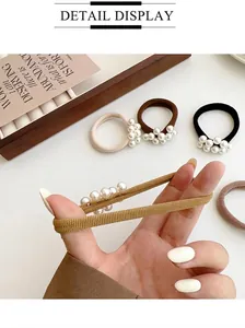 Detail van elastische haarelastiekjes met vijf witte parels in neutrale kleuren