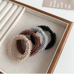 Détail d'élastiques à cheveux tressés neutres dans une boîte à bijoux en bois