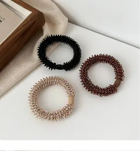 Détail de trois élastiques à cheveux spirales tissés en noir, marron foncé et champagne