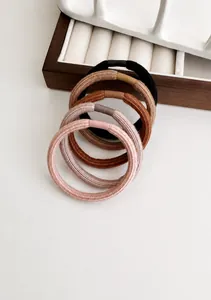Detail of ribbed texture and earth-toned elastic hair bands on white surface