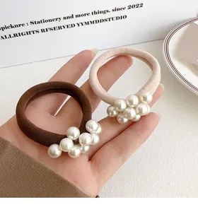 Detail van elastische koffie- en abrikooskleurige haarelastiekjes met witte parels