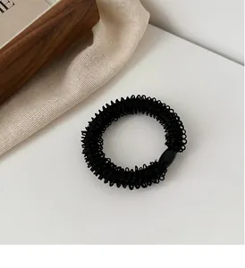 Gros plan d'un chouchou tressé noir avec texture en spirale et joint élastique robuste