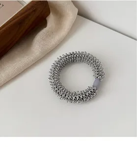 Détail d'un élastique spirale argenté sur un fond esthétique à la texture raffinée
