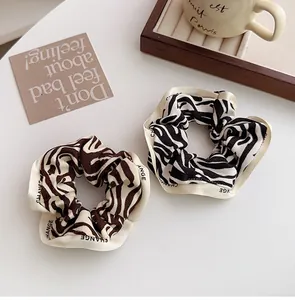 Detail of zebra pattern hair scrunchies with 'CHANGE' ribbon and premium fabric texture