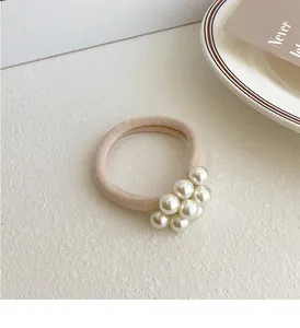 Detailweergave van beige elastische haarelastiek met glanzende witte parels en textuur