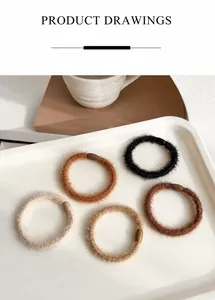 Detailed close-up of plush elastic hair ties in five earthy tones on a cream tray