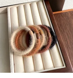 Close-up of plush elastic scrunchies in earth tones displayed in a velvet tray
