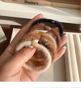 Detail shot of plush hair ties in earthy tones like black, brown, and beige faux fur
