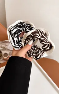 Macro detail of zebra print scrunchie showing satin texture and CHANGE letter ribbon