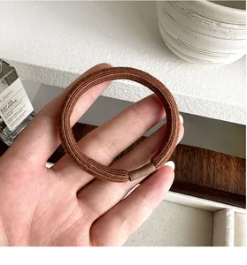Close-up of thick elastic brown hair tie with fabric texture held in hand