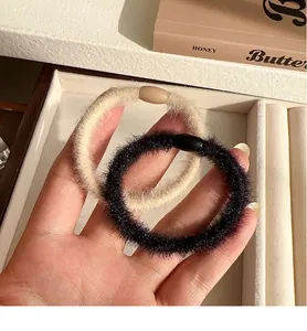 Detailed close-up of beige and black plush scrunchies with soft velvet texture