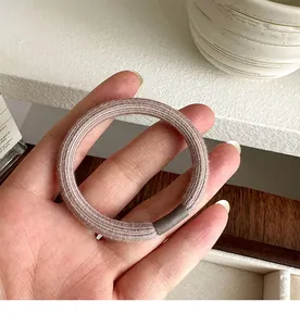 Close-up of a seamless thick elastic hair tie with ribbed texture in dusty rose color
