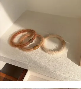 Close-up of soft plush hair ties in caramel, beige and cream for autumn winter