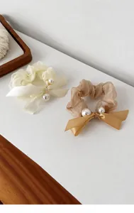 Close-up of elegant cream and champagne gauze hair scrunchies with pearls and bows