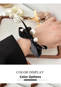 Detailed view of satin bow hair scrunchies with large pearls in black and beige colors