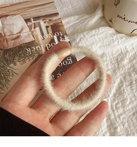 Close-up of soft creamy white plush hair scrunchie with a smooth connecting buckle