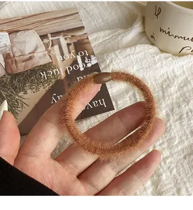 Close-up of soft brown plush scrunchie texture with durable plastic buckle detail