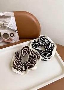 Close-up of zebra pattern hair scrunchies with CHANGE letter ribbon detail in a tray