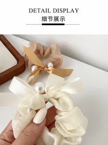 Detail display of handmade pearl embellishments on soft mesh bow scrunchie