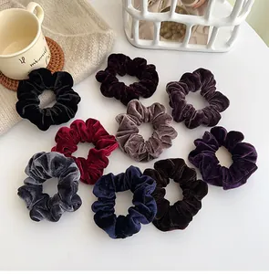 Detail view of nine-piece velvet scrunchie set in deep autumn colors on white desk