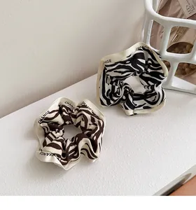 Detail of zebra pattern hair scrunchies with CHANGE text border on a modern white background