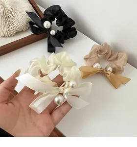 Detailed close-up of three chiffon scrunchies with silk bows and elegant pearls