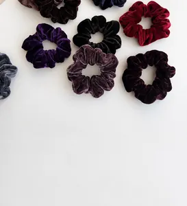 Macro view of plush velvet scrunchies in assorted dark colors showing soft texture