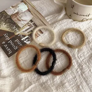 Set of five plush hair scrunchies in cream and earth tones on white fabric background