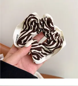 Macro view of zebra print scrunchie with CHANGE text ribbon detail and fabric texture