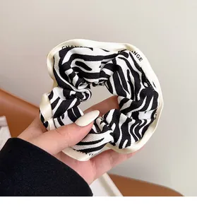 Close-up of zebra print scrunchie with CHANGE letter ribbon and silk texture