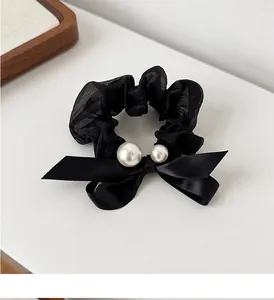 Detail of black organza scrunchie with satin bow and white faux pearl accents