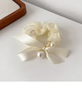 Detail of cream organza scrunchie with satin bow and two lustrous pearl accents