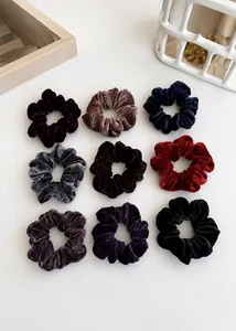 Detailed view of nine assorted velvet scrunchies in various rich autumn and winter colors