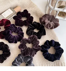 Detail view of large velvet scrunchies in multiple dark colors on a soft knit background