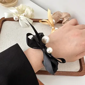 Elegant organza scrunchies with bow and pearl detail in black, cream, and champagne gold