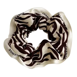 French retro zebra pattern hair scrunchie with CHANGE lettering on cream ribbon