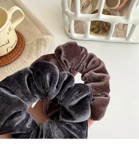 Detail view of large velvet scrunchies in dark grey and mauve purple colors