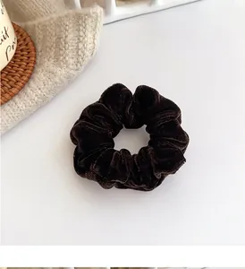 Detailed texture of a large dark brown velvet scrunchie on a cozy home setting