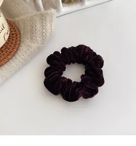 Macro shot of high-elasticity dark purple velvet scrunchie on cozy knit background