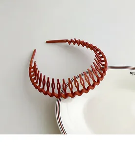 Gros plan du serre-tête ondulé rouge brique antidérapant avec peigne sur assiette
