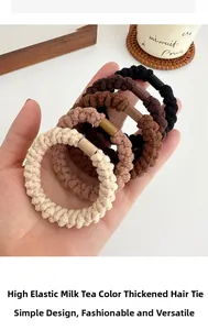 Dettaglio di cinque elastici per capelli spessi in colori neutri tè al latte su sottobicchiere