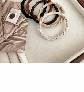 Close-up of four earthy tone elastic hair ties with woven texture and leather covers