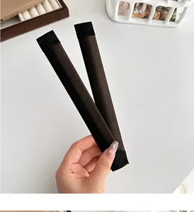 Close-up of two dark brown bun makers with a fine fibrous texture on a white background