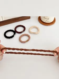 Dettaglio di elastici per capelli intrecciati in toni neutri con prova di elevata elasticità