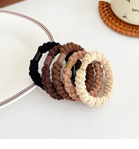 Dettaglio di cinque elastici per capelli spessi nei toni marrone e beige per code alte