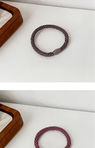 Detail of high-elastic braided hair ties in dark grey and burgundy with seamless joints