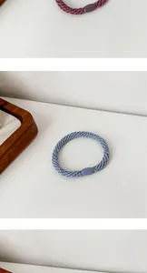 Detailed close-up of thick woven hair ties in blue and purple with matching oval buckles