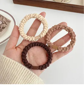 Dettaglio di tre elastici per capelli spessi nei toni della terra beige e caffè
