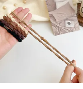 Dettaglio di cinque elastici per capelli intrecciati color terra ad alta elasticità e tenuta